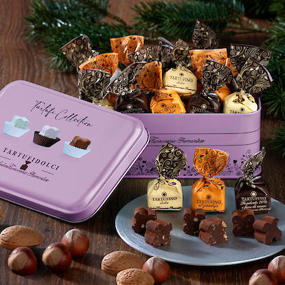 Geschenkdose mit Tartufi-Pralinen in verschiedenen Sorten und Nüssen weihnachtlich arrangiert.