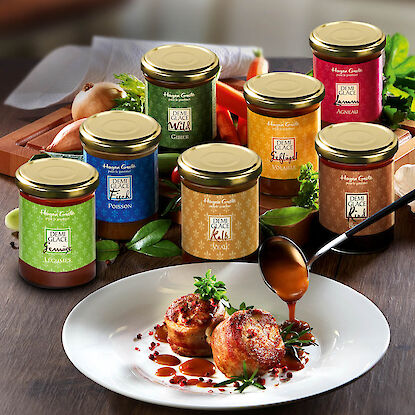 Verschiedene Hagen-Grote Demi-Glace-Sorten in Gläsern hinter einem Teller mit Fleischmedaillons, die mit Sauce nappiert werden.