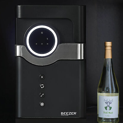 Schwarzer Getränkekühler mit beleuchtetem Display, daneben eine Weinflasche im Regal.