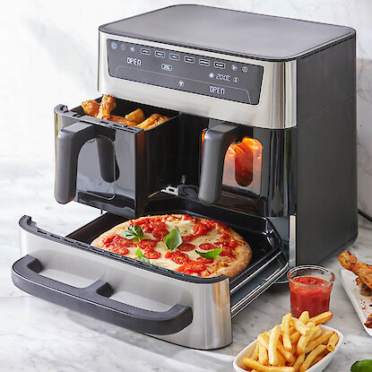 Friteuse &agrave; air chaud &agrave; deux tiroirs et grand compartiment, avec wings et pizza, accompagn&eacute;e de frites et sauce sur marbre.