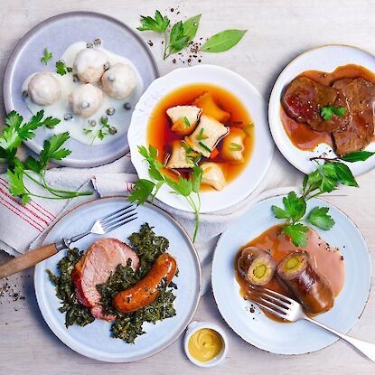 Cinq plats allemands : boulettes K&ouml;nigsberg, ravioles souabes, r&ocirc;ti de b&oelig;uf, chou fris&eacute; au kassler et roulades, servis en assiettes.