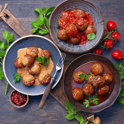 Trois assiettes de boulettes : sauce tomate, sauce cr&egrave;me claire et sauce brune, d&eacute;cor&eacute;es d&rsquo;herbes fra&icirc;ches.