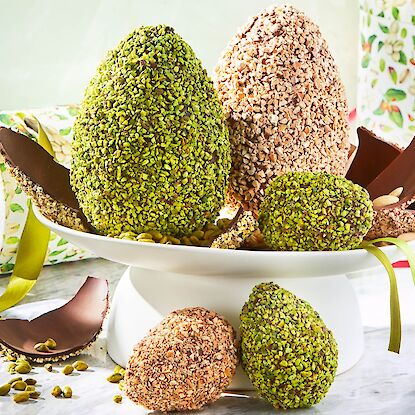 &OElig;ufs de P&acirc;ques en chocolat enrob&eacute;s de pistaches et de fruits secs sur pr&eacute;sentoir, partiellement ouverts, d&eacute;coratifs