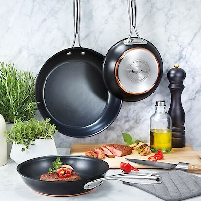 Hagen-Grote-Bratpfannen aus der Eigenmarke, antihaftbeschichtet, mit Steak, Kr&auml;utern, &Ouml;lflasche und K&uuml;chenzubeh&ouml;r arrangiert.