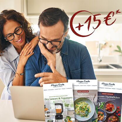 Paar am Laptop mit Hagen Grote Prospekten und 15 &euro; Gutschein-Aktion im Hintergrund