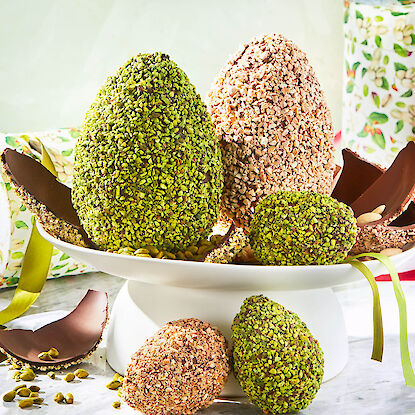 Schokoladen-Ostereier mit Pistazien- und Nussmantel, dekorativ arrangiert auf Etagere, festliche Oster-S&uuml;&szlig;igkeiten.