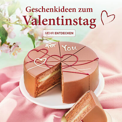 Herzf&ouml;rmige Geschenkbox mit Pralinen in Goldfolie, ge&ouml;ffnet auf hellem Hintergrund, mit Aufschrift &bdquo;Alles Liebe zum Valentinstag&ldquo;.