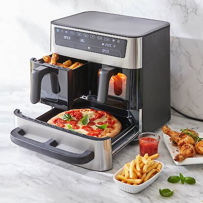 Friteuse &agrave; air chaud &agrave; deux tiroirs : pizza dans le compartiment inf&eacute;rieur, pilons de poulet au-dessus, appareil moderne sur plan de travail