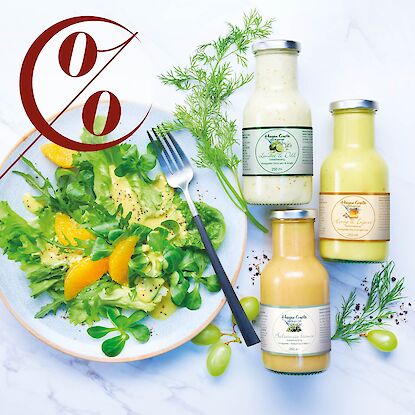 Salade verte fra&icirc;che aux quartiers d&rsquo;orange dans une assiette, trois bouteilles de vinaigrettes &agrave; c&ocirc;t&eacute;, symbole de r&eacute;duction en pourcentage