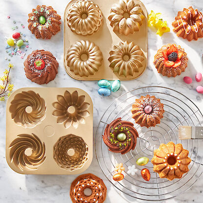 Backformen mit detailreichen Gugelhupf- und Bl&uuml;tenmotiven, darum dekorierte Mini-Kuchen und bunte Ostereier