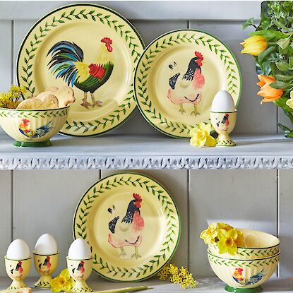 Vaisselle jaune avec motifs de coq et poule, assiettes, bols et coquetiers dispos&eacute;s avec des fleurs printani&egrave;res
