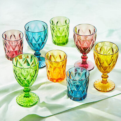 Verres color&eacute;s aux teintes vari&eacute;es et motifs taill&eacute;s, dispos&eacute;s de mani&egrave;re d&eacute;corative sur fond clair