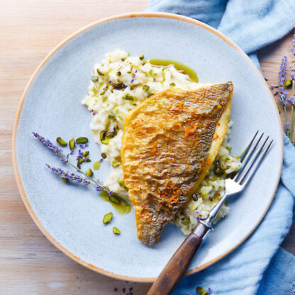 Filet de poisson po&ecirc;l&eacute; sur risotto cr&eacute;meux aux herbes et &agrave; l&rsquo;huile, dress&eacute; sur assiette claire avec couvert