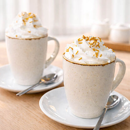 Deux tasses en c&eacute;ramique avec boisson chaude et chantilly, d&eacute;cor&eacute;es de vermicelles, sur soucoupes en bois